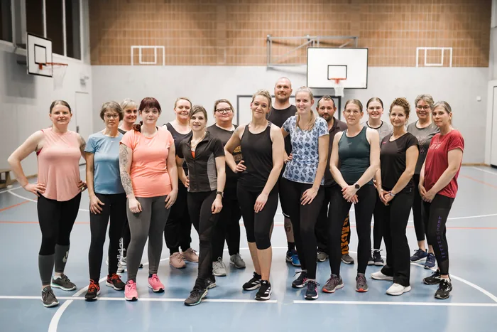 Die Kickfit-Gruppe in Sportkleidung nebeneinander in der Turnhalle